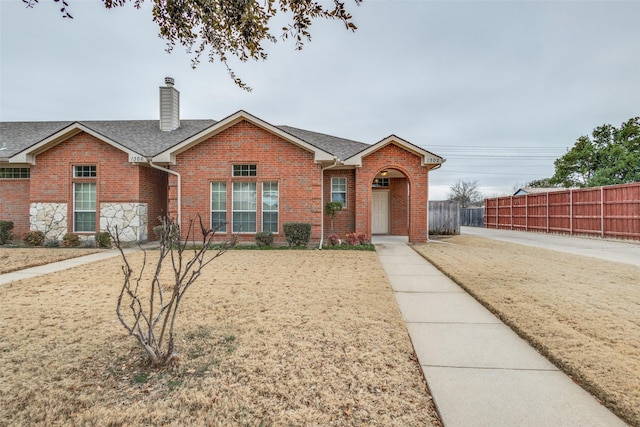 ranch-style house featuring brick siding, fence, a chimney, and roof with shingles