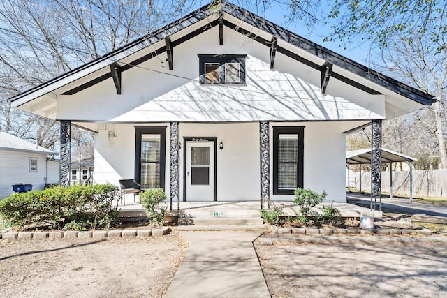 view of front of house featuring driveway, a porch, fence, and a detached carport