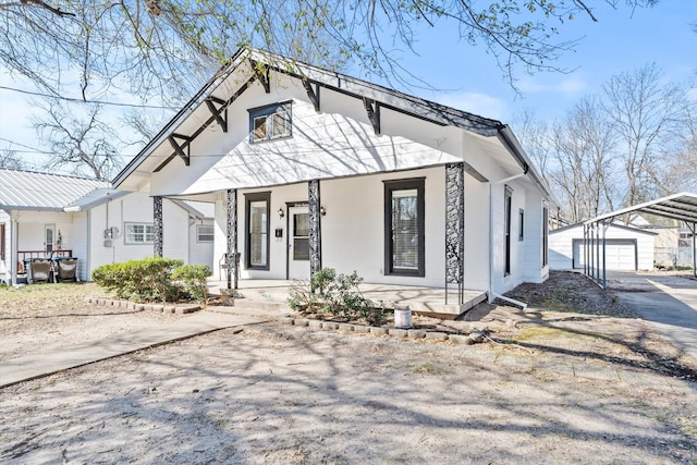 bungalow-style home featuring covered porch, driveway, an outdoor structure, and a garage