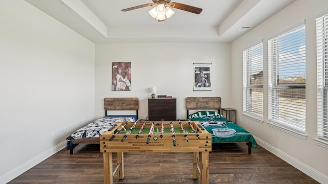 bedroom featuring baseboards, a raised ceiling, and wood finish floors