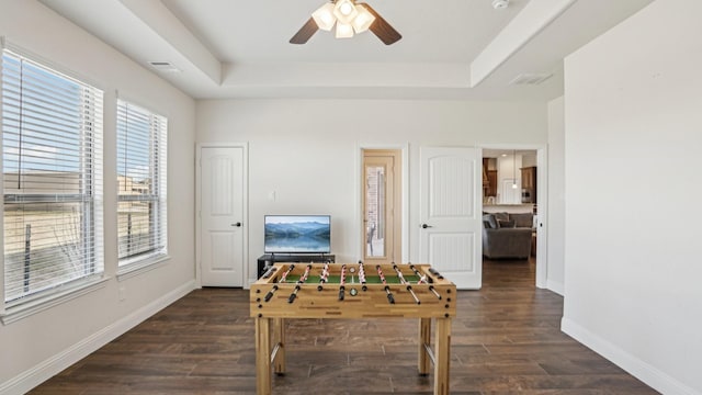 playroom with dark wood-style floors, ceiling fan, a tray ceiling, and baseboards