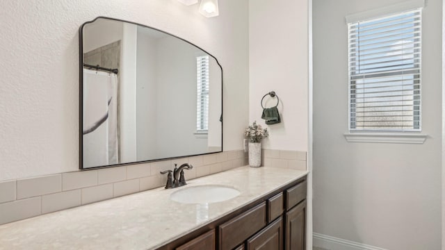 bathroom featuring backsplash, vanity, and baseboards