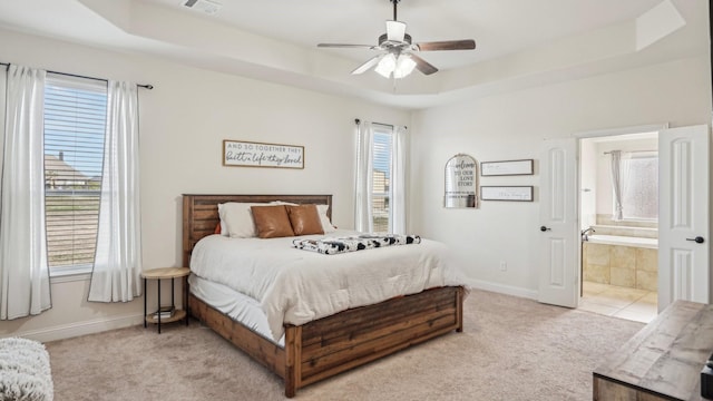 bedroom with a raised ceiling, visible vents, light carpet, connected bathroom, and baseboards