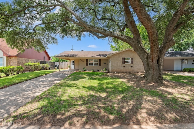 ranch-style home with concrete driveway, fence, a front yard, a carport, and brick siding