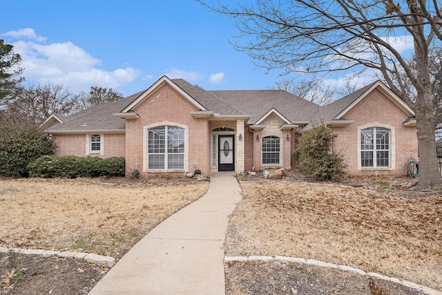 ranch-style house with a shingled roof and brick siding