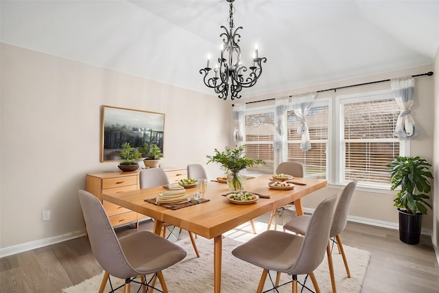 dining area with a notable chandelier, baseboards, vaulted ceiling, and wood finished floors