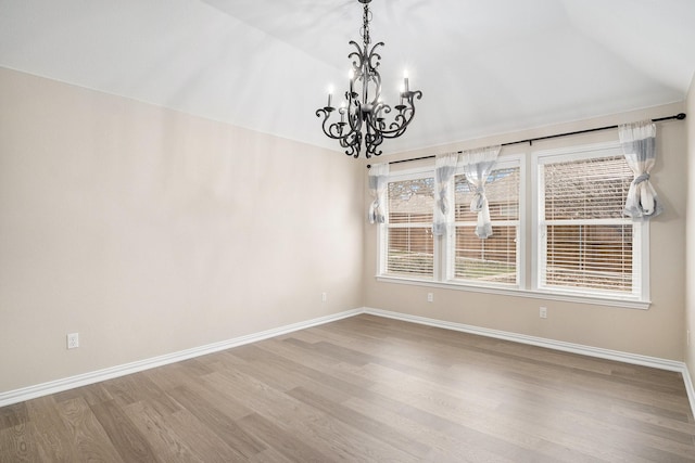 empty room featuring lofted ceiling, light wood-style flooring, and baseboards