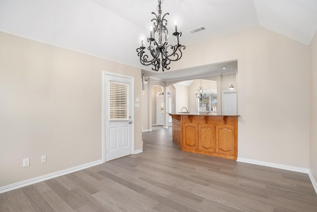 interior space with arched walkways, lofted ceiling, visible vents, an inviting chandelier, and light wood-type flooring