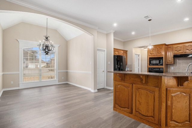 kitchen with light wood finished floors, tasteful backsplash, brown cabinetry, decorative light fixtures, and black appliances