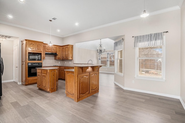 kitchen featuring black appliances, light countertops, decorative light fixtures, and a center island