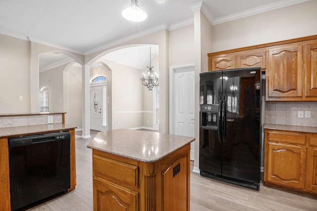 kitchen with a center island, light countertops, decorative backsplash, black appliances, and brown cabinetry