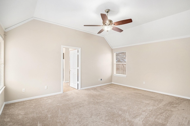 empty room featuring crown molding, light colored carpet, a ceiling fan, vaulted ceiling, and baseboards