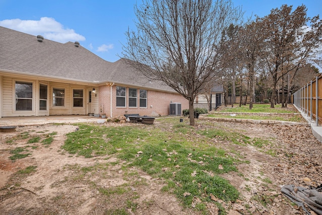 back of house with a shingled roof, central AC, brick siding, and a fenced backyard