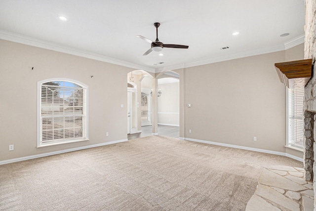 unfurnished living room with arched walkways, ornamental molding, a ceiling fan, and light colored carpet