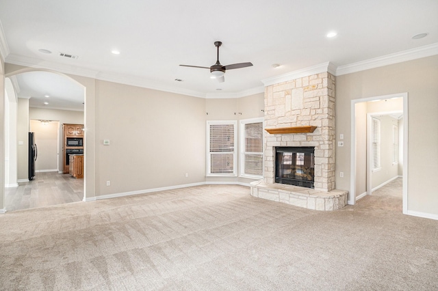 unfurnished living room featuring light carpet, visible vents, arched walkways, crown molding, and a fireplace