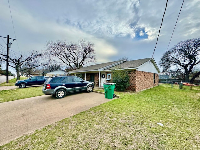 view of home's exterior featuring driveway, a lawn, and brick siding