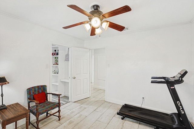 exercise area with light wood-style flooring, visible vents, a ceiling fan, baseboards, and ornamental molding