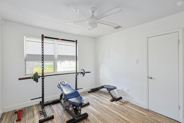 workout room featuring visible vents, light wood-style floors, ceiling fan, a textured ceiling, and baseboards