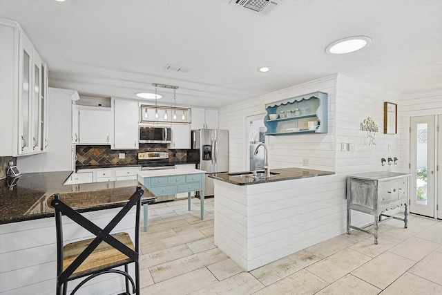 kitchen featuring dark countertops, appliances with stainless steel finishes, white cabinetry, and a peninsula