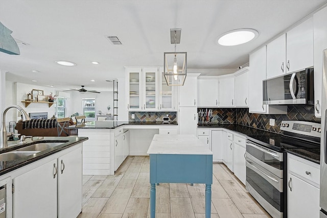 kitchen featuring stainless steel appliances, dark countertops, a center island, and white cabinetry