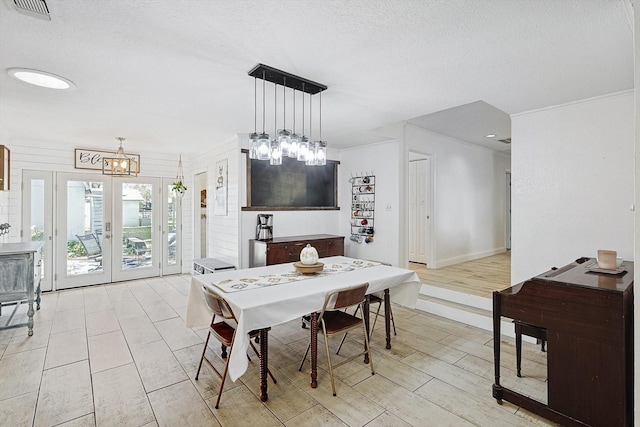 dining room with french doors, a notable chandelier, light wood finished floors, visible vents, and a textured ceiling