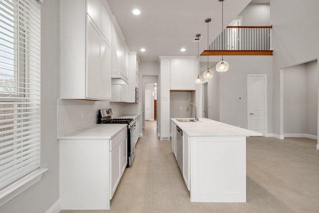 kitchen featuring an island with sink, hanging light fixtures, stainless steel appliances, white cabinetry, and a sink