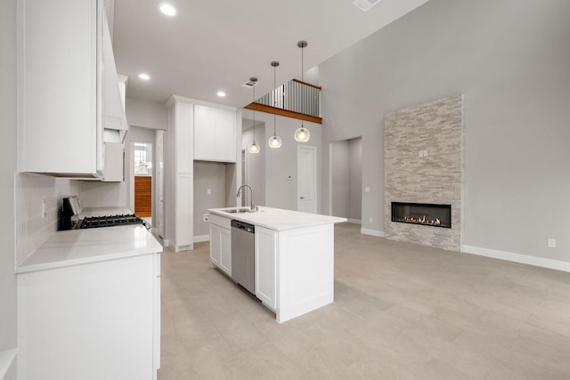 kitchen with hanging light fixtures, stove, white cabinets, a kitchen island with sink, and dishwasher