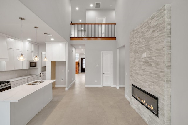 kitchen featuring a sink, visible vents, white cabinets, light stone countertops, and decorative light fixtures