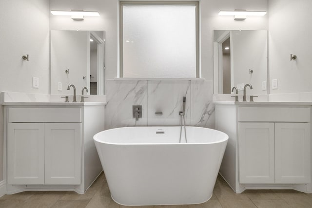 bathroom featuring a freestanding bath, two vanities, a sink, and tile patterned floors