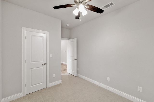 unfurnished bedroom featuring light carpet, baseboards, visible vents, and a ceiling fan