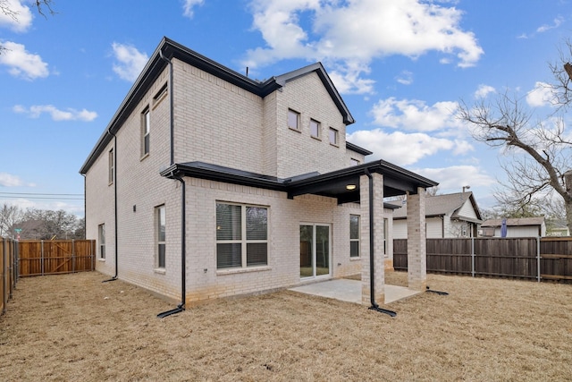 rear view of house with brick siding, a fenced backyard, a yard, and a patio