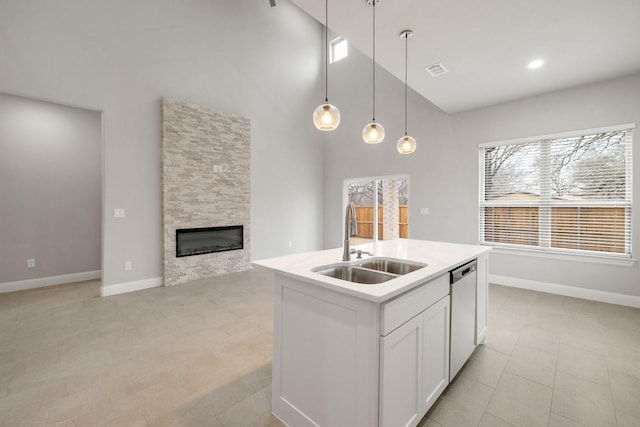 kitchen with pendant lighting, stainless steel dishwasher, white cabinetry, a sink, and an island with sink