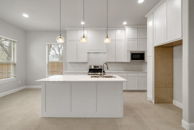 kitchen featuring light countertops, a sink, a kitchen island with sink, and built in microwave