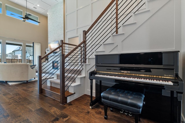 staircase with recessed lighting, a towering ceiling, and wood finished floors