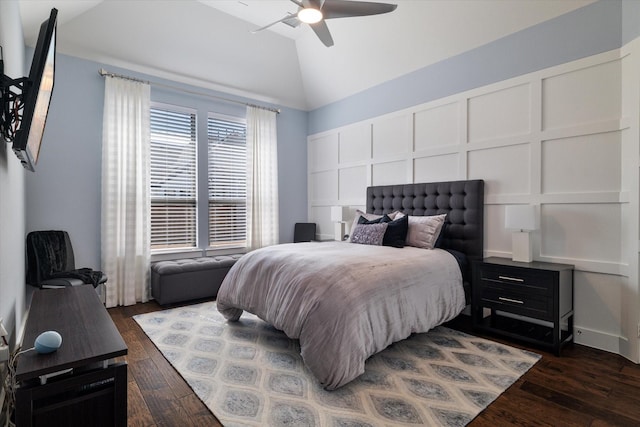 bedroom featuring dark wood-style floors, vaulted ceiling, and a decorative wall