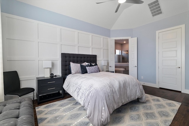 bedroom with lofted ceiling, dark wood-style flooring, visible vents, and a decorative wall