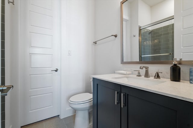 full bath featuring toilet, tile patterned floors, tiled shower, and vanity