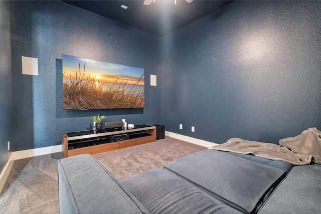 carpeted home theater room featuring baseboards and a textured wall