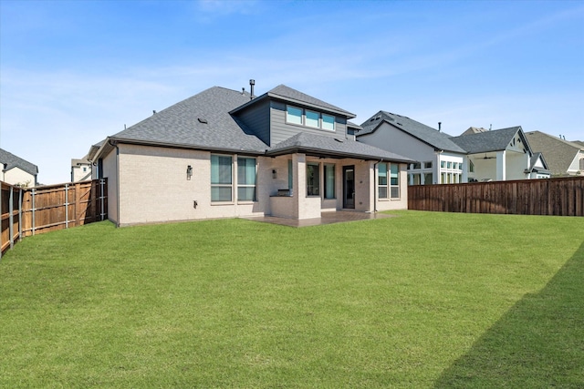 back of house featuring brick siding, a patio, roof with shingles, a lawn, and a fenced backyard