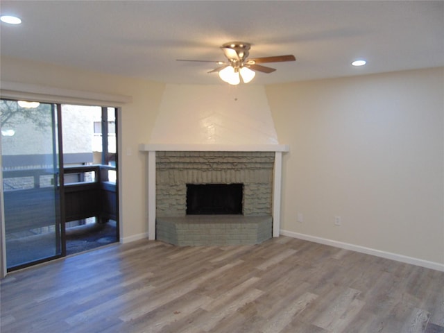 living area with a ceiling fan, wood finished floors, baseboards, recessed lighting, and a brick fireplace