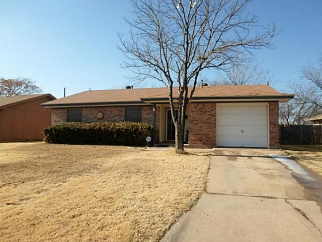 ranch-style home featuring brick siding, concrete driveway, an attached garage, and fence