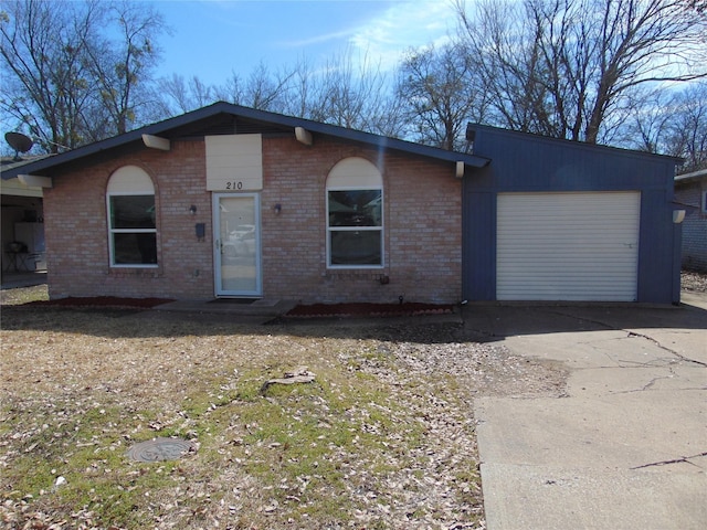 view of front of home featuring a garage, concrete driveway, and brick siding