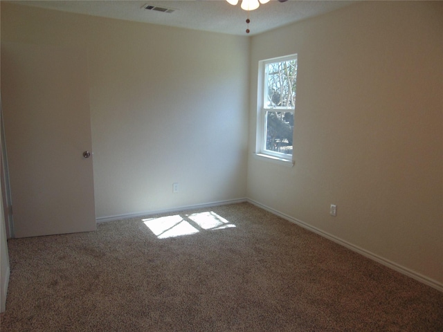 carpeted spare room featuring a ceiling fan, visible vents, and baseboards