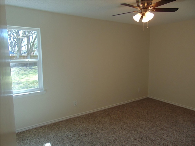 carpeted empty room with a ceiling fan and baseboards