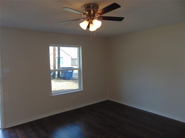 spare room with dark wood-style floors, baseboards, and a ceiling fan