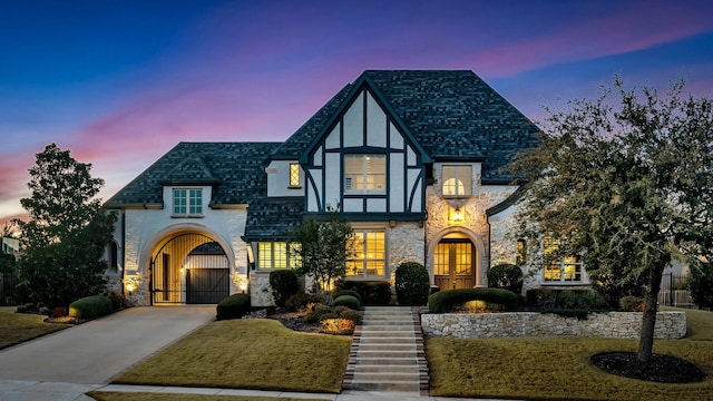 view of front of house with concrete driveway, stone siding, a gate, french doors, and stucco siding