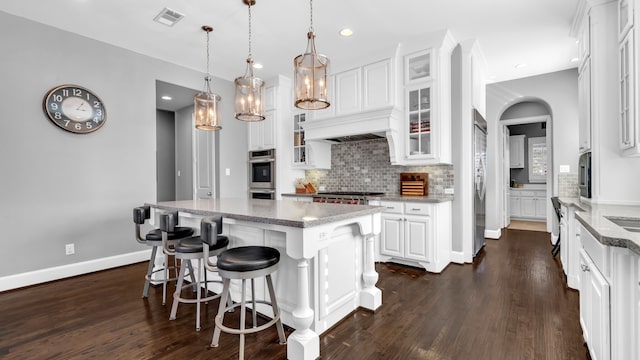 kitchen featuring appliances with stainless steel finishes, white cabinetry, backsplash, and dark wood-type flooring