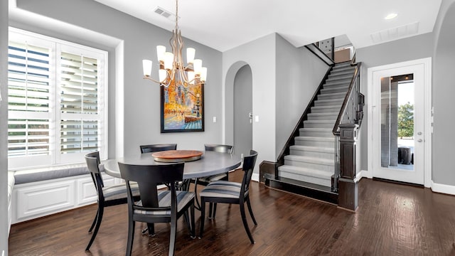 dining area with stairway, dark wood-style flooring, visible vents, and an inviting chandelier