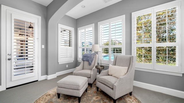 living area with baseboards, arched walkways, and carpet flooring