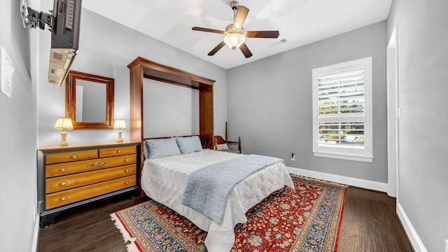 bedroom featuring dark wood-type flooring, a ceiling fan, visible vents, and baseboards